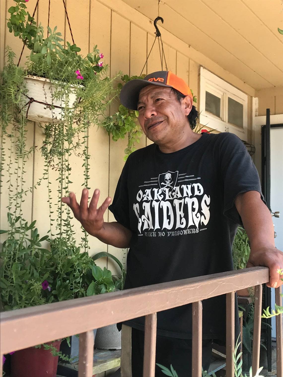 Guillermo Hernandez stands outside his second story apartment in Calwa surrounded by his plants. His walkway stands out against the dirt lot that the tan apartment complex sits on.