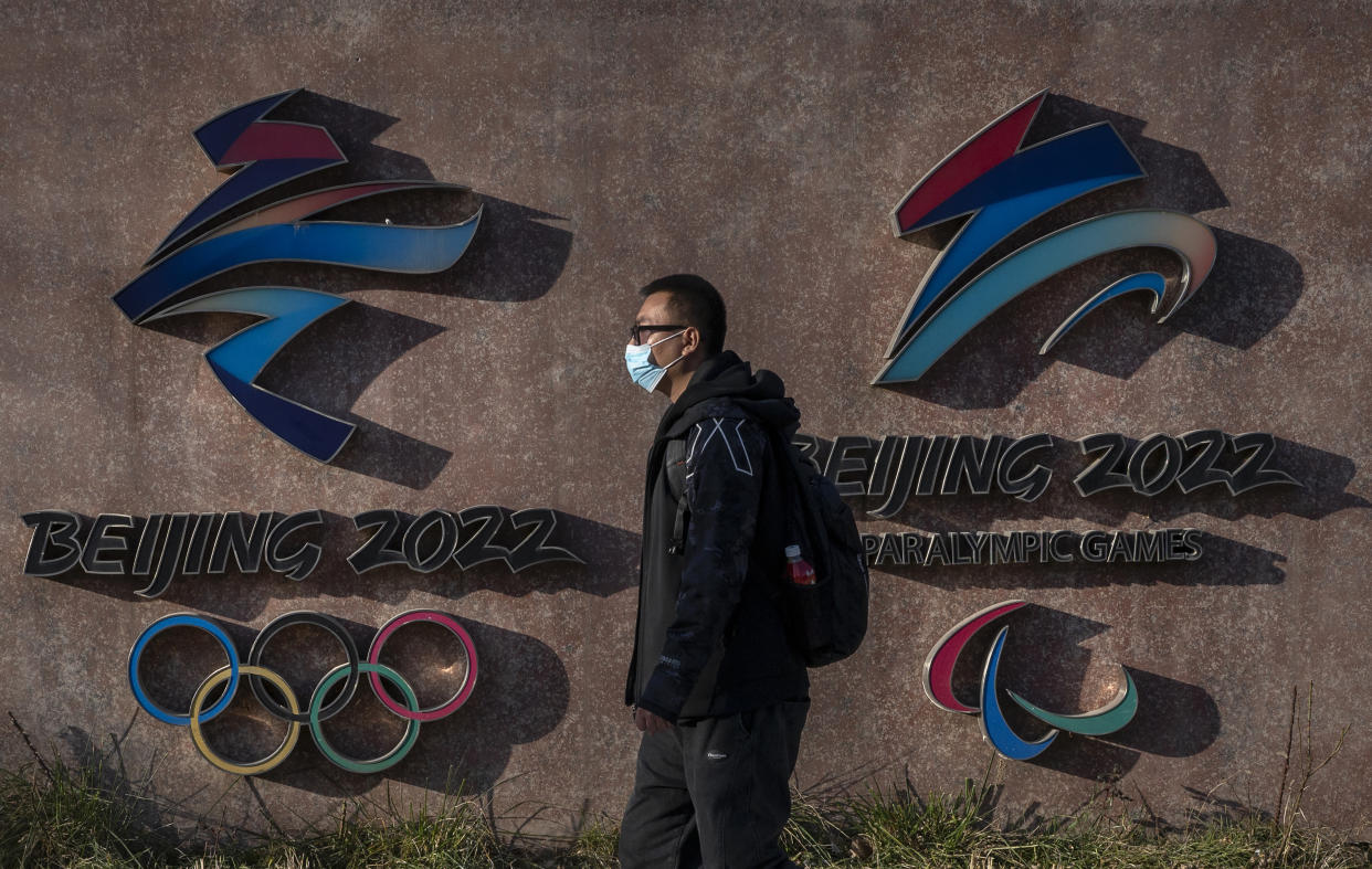 BEIJING, CHINA - DECEMBER 07: A visitor walks by the logos for the Beijing 2022 Winter Olympics and Paralympics at Shougang, a former power plant which now also houses the headquarters of the Beijing Organizing Committee of the Olympic Games, on December 7, 2021 in Beijing, China. The games are set to open on February 4, 2022.(Photo by Kevin Frayer/Getty Images)