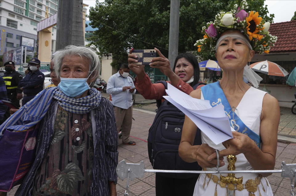 Cambodian-American lawyer Theary Seng, dressed in a pageant costume that reads "Lady Justice", stands outside Phnom Penh Municipal Court in Phnom Penh, Cambodia, Tuesday, May 3, 2022. Tuesday is the the final day of hearings for her trial on treason and a related charge for which she could receive a prison sentence of up to 12 years. (AP Photo/Heng Sinith)