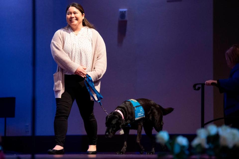 CASA’s courthouse emotional support dog Remmy and handler Naomi walk on stage to receive an award during a candlelight ceremony as a part of National Crime Victims’ Rights Week at First Baptist Church of Gulfport on Tuesday, April 23, 2024.