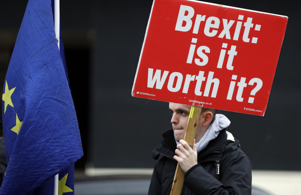 A protester holds a banner in London, Wednesday, Jan. 16, 2019. British lawmakers overwhelmingly rejected Prime Minister Theresa May's divorce deal with the European Union on Tuesday, plunging the Brexit process into chaos and triggering a no-confidence vote that could topple her government. (AP Photo/Frank Augstein)