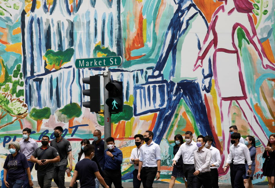 Office workers wearing protective face masks cross a street, during the coronavirus disease (COVID-19) outbreak, in the central business district in Singapore January 11, 2021. REUTERS/Edgar Su