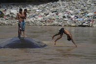 A man who is part of a migrant caravan, jumps into the Huixtla River, Chiapas state, Mexico, Tuesday, Oct. 26, 2021, on a day of rest before continuing their trek across southern Mexico to the U.S. border. (AP Photo/Marco Ugarte)