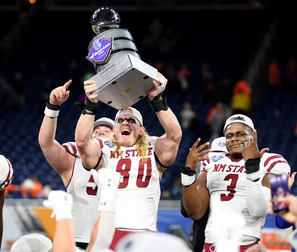 Dec 26, 2022; Detroit, Michigan, USA; New Mexico State University linebacker Trevor Brohard (80) hoists the Quick Lane Bowl trophy over his head as he and his teammates celebrate their win over Bowling Green State University in the 2022 Quick Lane Bowl at Ford Field. Mandatory Credit: Lon Horwedel-USA TODAY Sports