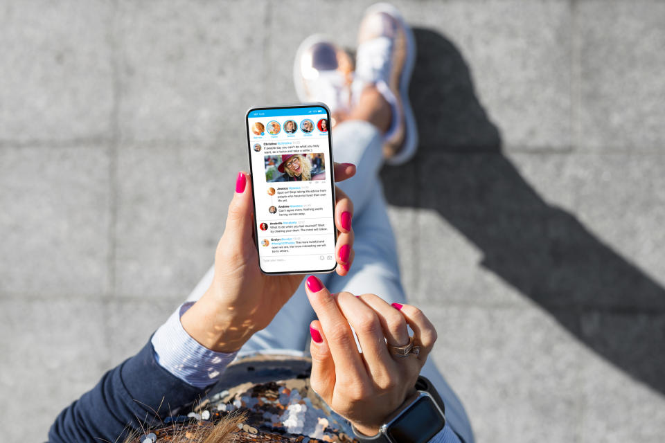 Person holding a smartphone with social media feed onscreen, viewed from above