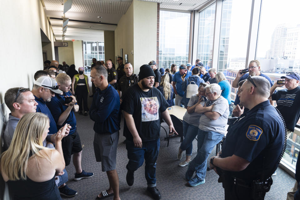 Supporters of Christopher Schurr gather in the hallway and listen on a live stream outside of Kent County District Court as Grand Rapids Police officer Schurr appeared on video from jail, Friday, June 10, 2022 in Grand Rapids, Mich. A judge facing a packed courtroom set bond Friday at $100,000 for Schurr, a Michigan police officer charged with second-degree murder in the death of Patrick Lyoya, a Black man who was shot in the back of the head in April. (Joel Bissell/The Grand Rapids Press via AP)