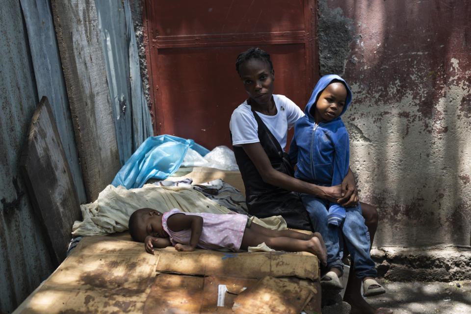 Lovely Benjamin poses for a photo with her children at a makeshift shelter in Jean-Kere Almicar's front yard, in Port-au-Prince, Haiti, Sunday, June 4, 2023. Displaced by a surge in gand violence, they live in Jean-Kere Almicar’s front yard along with other neighbors from Cite Soleil. (AP Photo/Ariana Cubillos)