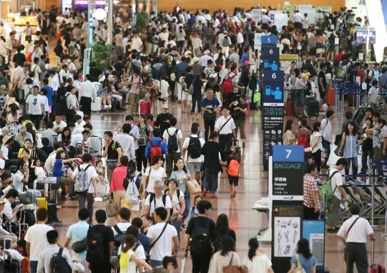 People crowd into the departure lobby at Tokyo's Haneda Airport on August 22, 2016 as hundreds of flights are cancelled due to Typhoon Mindulle