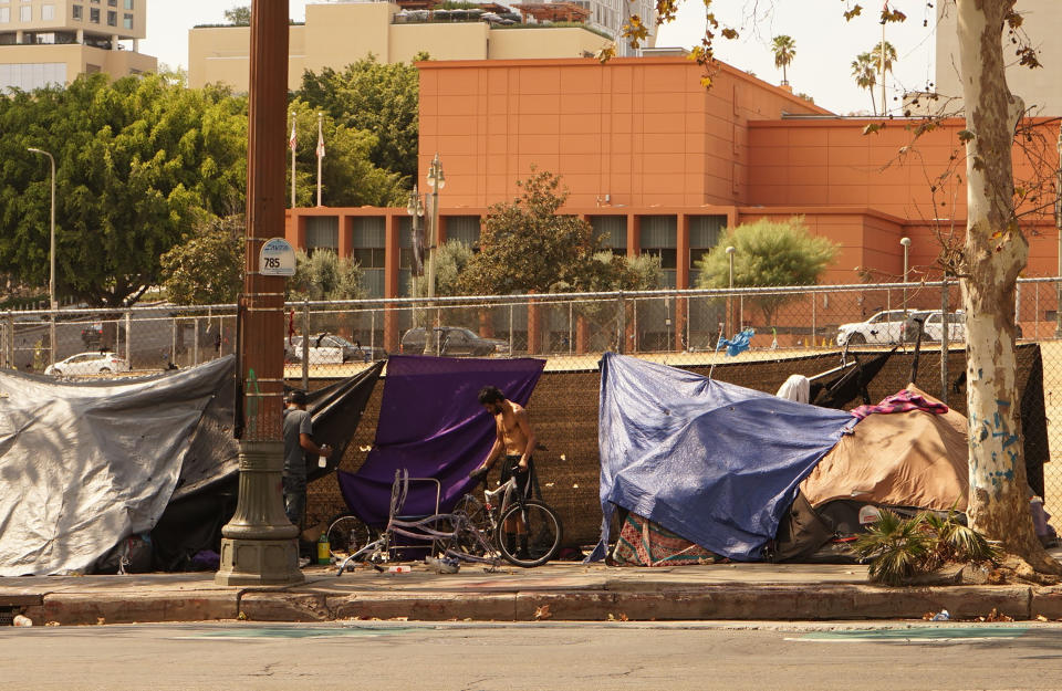 Four tents housing the homeless line a downtown sidewalk.