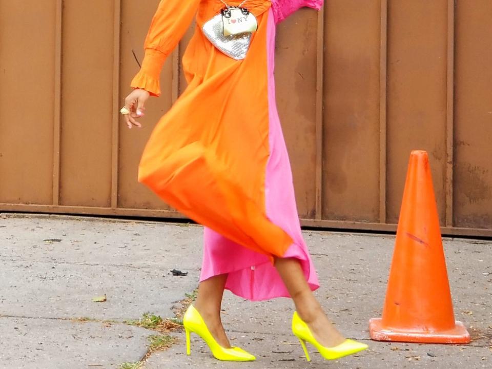 celebrity stylist wearing a bright orange and pink dress with yellow heels