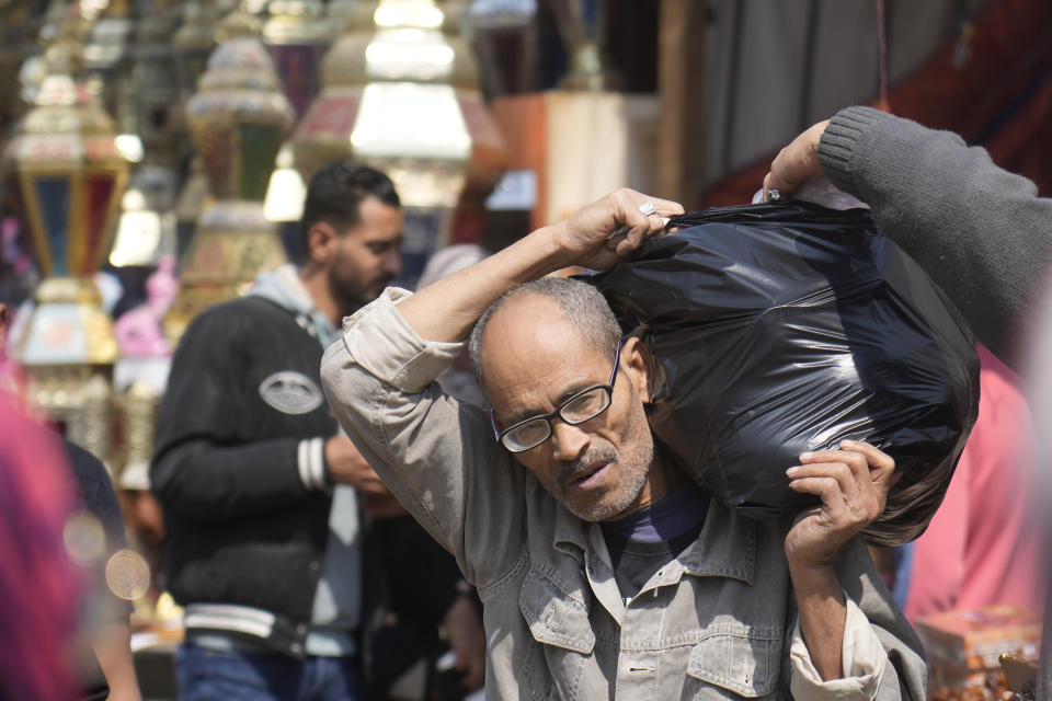 A man carries his shopping food ahead of the upcoming Muslim fasting month of Ramadan, in Cairo, Egypt, Tuesday, March 21, 2023. (AP Photo/Amr Nabil)