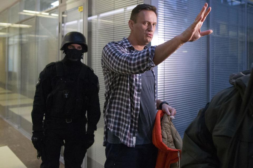 Russian opposition leader Alexei Navalny speaks to the media as a policeman stands guard at the Foundation for Fighting Corruption office in Moscow (AP)