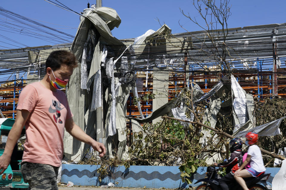 Residents pass by metal sheets wrapped on electrical posts due to Typhoon Rai in Cebu province, central Philippines on Monday Dec. 20, 2021. The death toll in the strongest typhoon to batter the Philippines this year continues to rise and the governor of an island province especially hard-hit by Typhoon Rai said there may be even greater devastation that has yet to be reported. (AP Photo/Jay Labra)