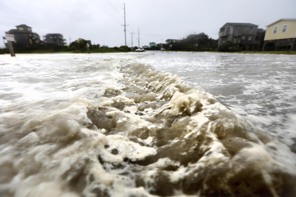 Ocean water breaches the dune line and rushes down Highway 12 in Frisco on Thursday.