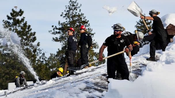PHOTO: Members of the California Army National Guard shovel snow from a rooftop after a series of winter storms dropped more than 100 inches of snow in the San Bernardino Mountains in Southern California, March 8, 2023, in Crestline, Calif. (Mario Tama/Getty Images)