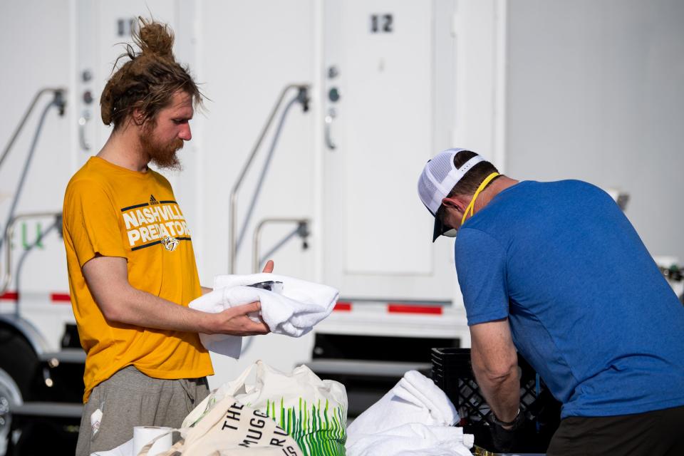 Jared Charles, left, receives a towel from Paul Schmitz at the ShowerUp trailer in Nashville on March 26.