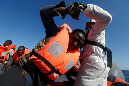 Rescuers of the Malta-based NGO Migrant Offshore Aid Station (MOAS) rescue migrants from a rubber dinghy in the central Mediterranean in international waters some 15 nautical miles off the coast of Zawiya in Libya, April 14, 2017. REUTERS/Darrin Zammit Lupi