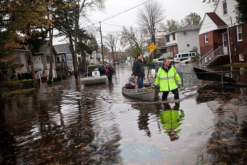 An emergency responder helps evacuate two people with a boat, after their neighborhood experienced flooding due to Hurricane Sandy, on October 30, 2012, in Little Ferry, New Jersey. 