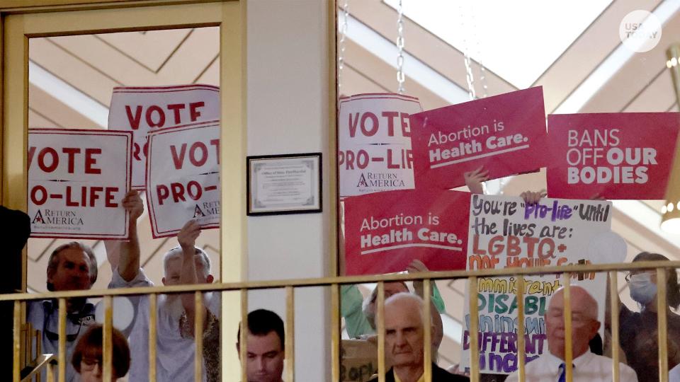 Protesters on both sides of the abortion issue hold signs on Tuesday evening at the N.C. General Assembly in Raleigh as state House members debated a new abortion law. The legislature voted to override Democratic Gov. Roy Cooper's veto and enact the new law. It bans nearly all abortions after the 12th week of pregnancy. The limit had been 20 weeks.