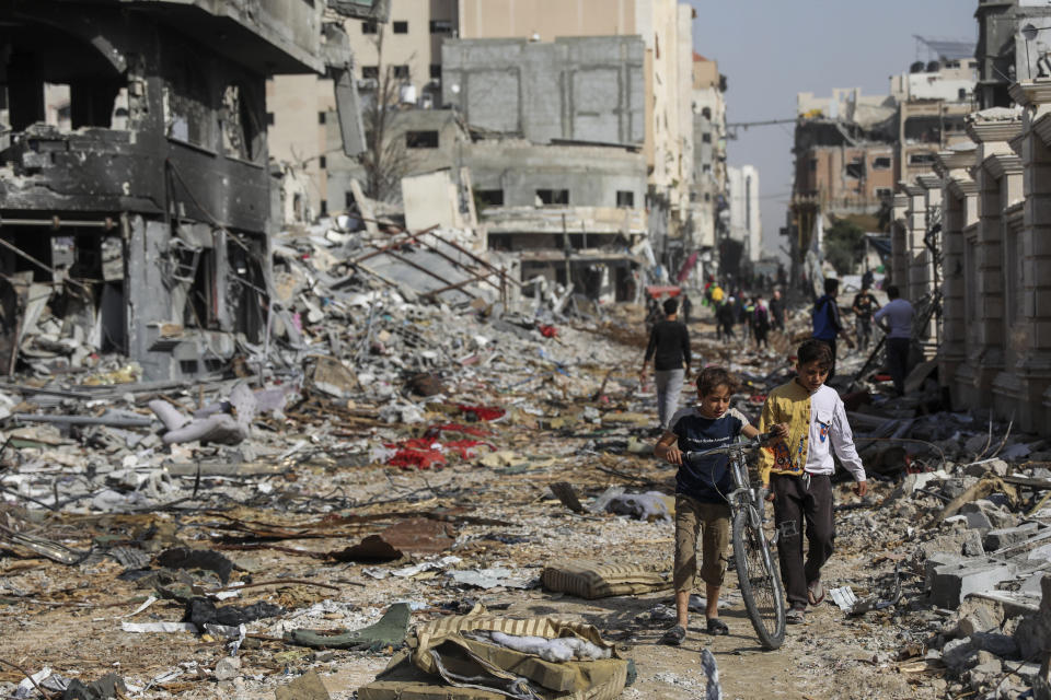 Palestinians walk through destruction in Gaza City on Friday, Nov. 24, 2023, as the temporary cease-fire between Israel and Hamas took effect. (AP Photo/Mohammed Hajjar)