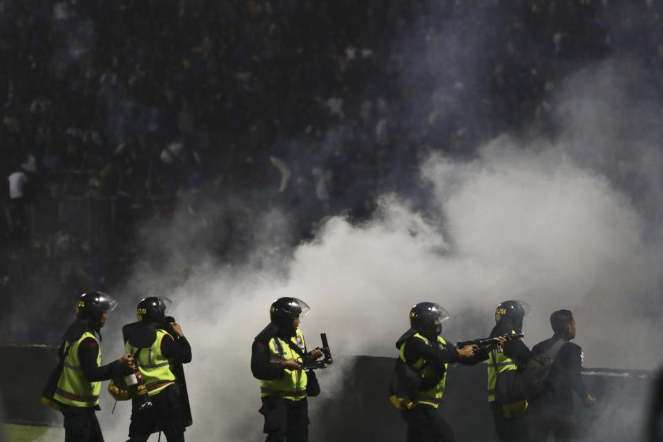 Police officers fire tear gas during clashes between fans at a soccer match at Kanjuruhan Stadium in Malang, East Java, Indonesia, Saturday, Oct. 1, 2022. Panic following police actions left over 100 dead, mostly trampled to death, police said Sunday. (AP Photo/Yudha Prabowo)