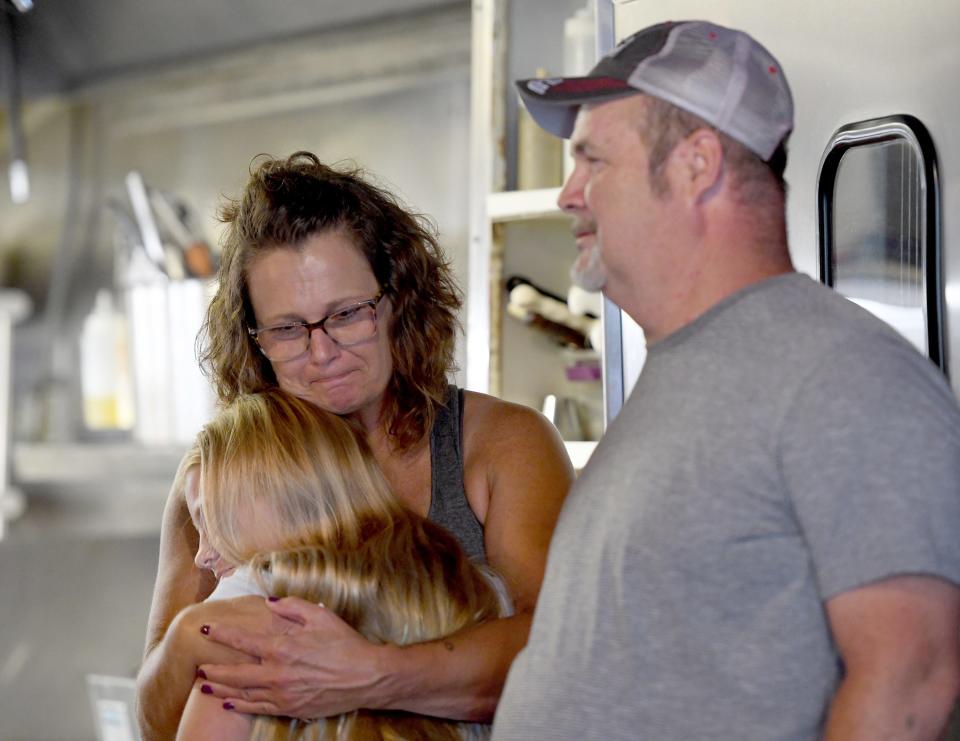 Rae Fry hugs granddaughter Charlie Galley, 11, with husband Tom Fry to right after their business, The Normandy Inn in Minerva, is sold by Kiko Auctioneers.
