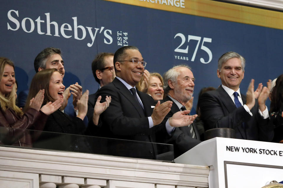 FILE - In this March 11, 2019, file photo Sotheby's Chairman Domenico De Sole, second from right, is applauded by CEO Tad Smith, right, and others as he rings the New York Stock Exchange opening bell to celebrate the company's 275th anniversary. BidFair USA is taking auction house Sotheby's private in a deal valued at $3.7 billion. BidFair USA will pay $57 per share, which is a 61% premium to the company's closing stock price. (AP Photo/Richard Drew, File)