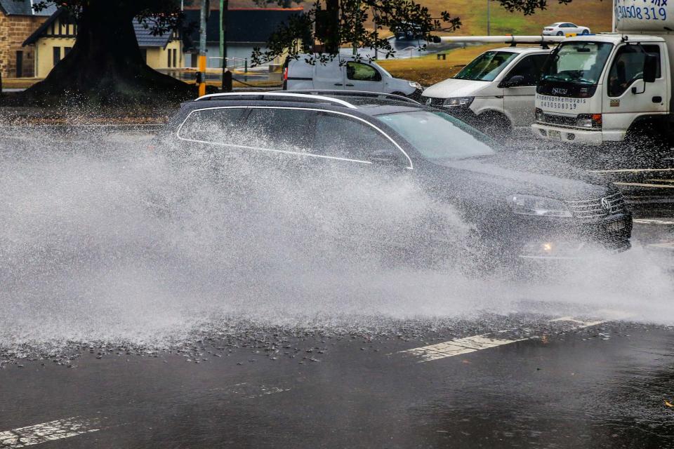 A car is seen traveling through flooded streets in Surry Hills, Sydney (Getty Images)