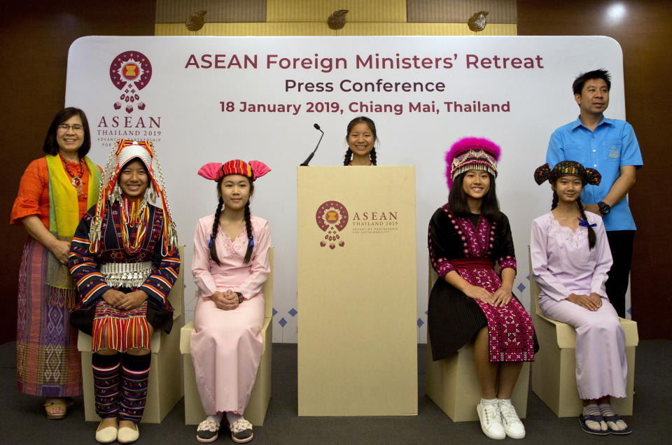 Thai school children in traditional tribal attire sit on cardboard chairs during a symbolic ceremony to receive cardboard school chairs made of recycled paper following the Association of Southeast Asian Nations (ASEAN) Foreign Ministers' retreat in Chiang Mai, Thailand, Friday, Jan. 18, 2019. (AP Photo/Gemunu Amarasinghe)