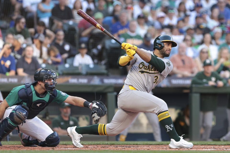 Oakland Athletics' Abraham Toro watches his RBI single next to Seattle Mariners catcher Cal Raleigh during the third inning of a baseball game Saturday, May 11, 2024, in Seattle. (AP Photo/Jason Redmond)
