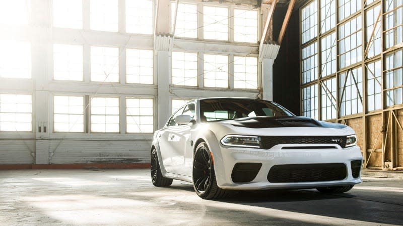 A photo of a white Dodge Challenger Hellcat in a hanger. 