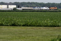 A freight train passes along side a derailed Amtrak train Tuesday, June 28, 2022, near Mendon, Mo. The train derailed after hitting a dump truck Monday killing the truck driver and other people on the train and injuring several dozen other passengers on the Chicago-bound train. (AP Photo/Charlie Riedel)