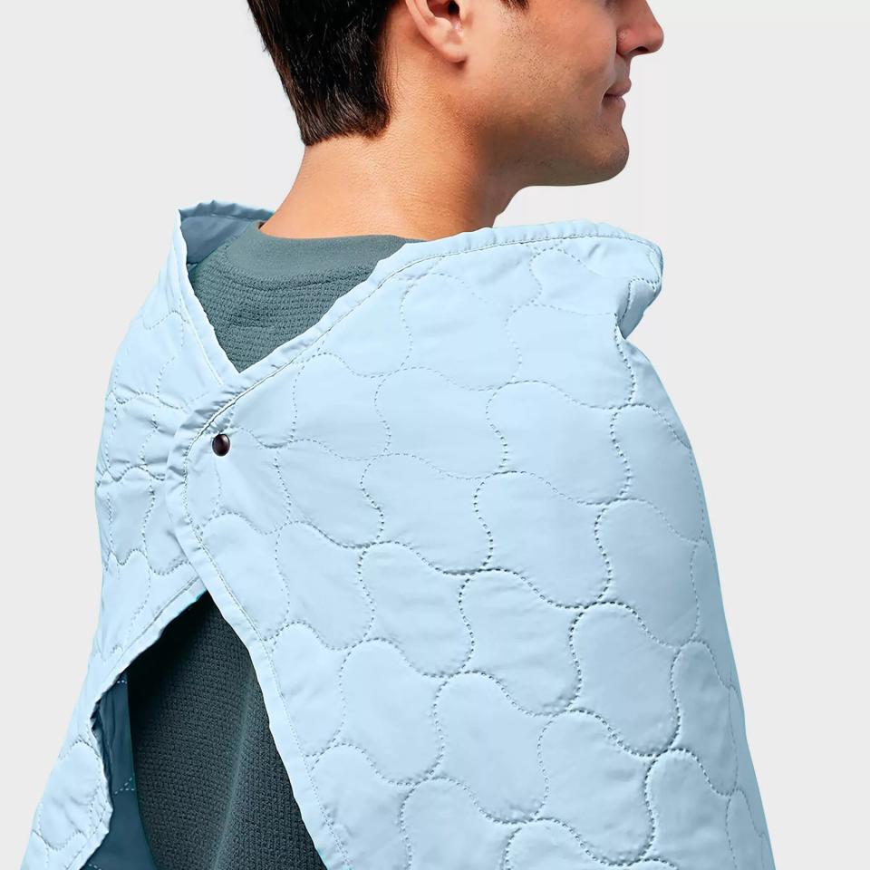 A model wearing the blanket with the button secured in the back