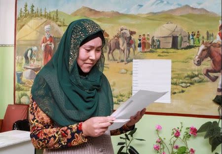 A woman studies her ballot at a polling station during the presidential election in the village of Kyzyl-Birdik, Kyrgyzstan October 15, 2017. REUTERS/Vladimir Pirogov