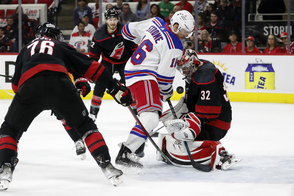 New York Rangers' Ryan Strome (16) drives the puck between Carolina Hurricanes' Brady Skjei (76) and Brett Pesce (22) only to have it blocked by goaltender Antti Raanta (32) during the first period of Game 1 of an NHL hockey Stanley Cup second-round playoff series in Raleigh, N.C., Wednesday, May 18, 2022. (AP Photo/Karl B DeBlaker)