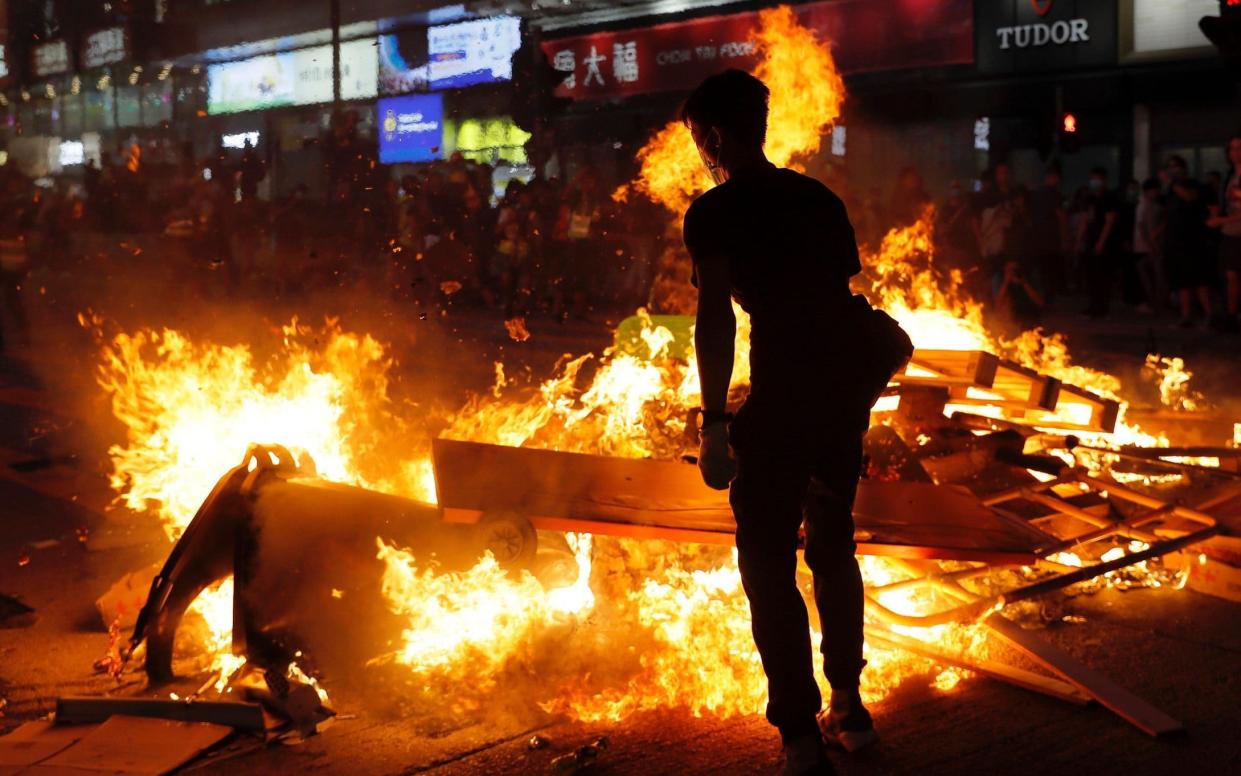 Protesters stand near burning items during a protest during a protest in Mong Kok, Hong Kong on Friday - AP