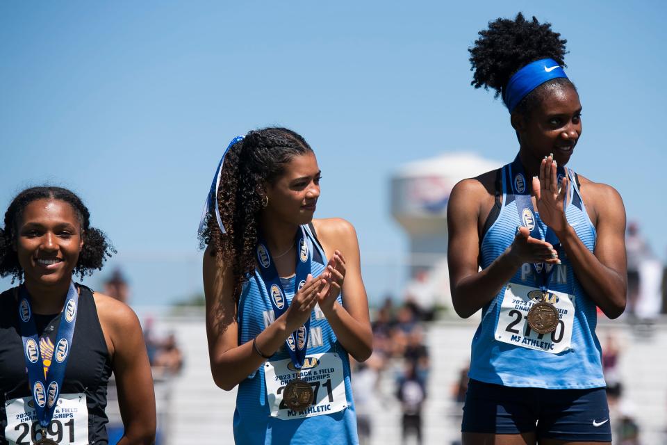 North Penn's Taylor Forbes (right) and Madison Gee applaud on the awards podium after placing fourth and sixth, respectively, in the 3A triple jump at the PIAA Track and Field Championships at Shippensburg University Friday, May 26, 2023.