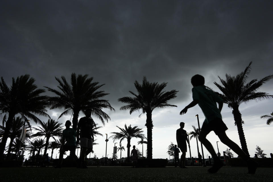 Young fans kick a soccer ball outside DRV Pink Stadium, home of the Inter Miami MLS soccer team, as they wait for gates to open for an event to present international superstar Lionel Messi the day after the team finalized his signing through the 2025 season, Sunday, July 16, 2023, in Fort Lauderdale, Fla. (AP Photo/Rebecca Blackwell)