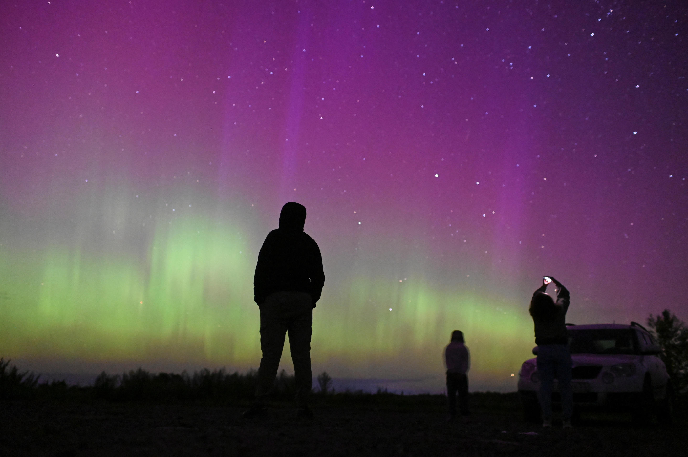 Menschen versammeln sich, um das spektakuläre Spektakel des jährlichen Perseiden-Meteorschauers und der Nordlichter in der Nähe des Dorfes Borodinka in der Region Omsk in Russland zu bewundern.