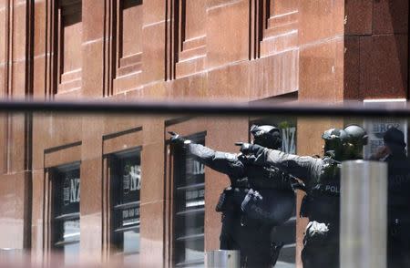 Police officers gesture near Lindt cafe in Martin Place, where hostages are being held, in central Sydney December 15, 2014. REUTERS/David Gray