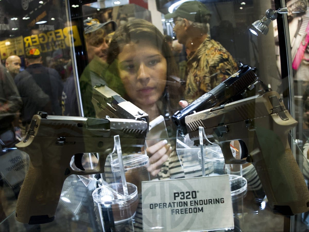 A prospective customer examines a case of Sig Sauer P320 handguns at the 2015 NRA Annual Convention in Nashville, Tennessee, not long after the model first went on sale to the public (Karen Bleier/AFP/Getty)