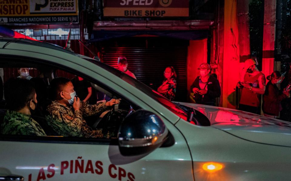 Police officers remind Filipinos of social distancing rules as they queue for a coronavirus vaccine - Ezra Acayan/Getty Images