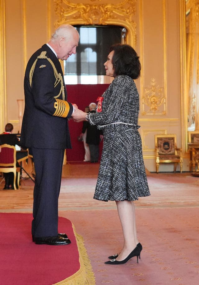 Dame Shirley Bassey, wearing a sparkly black and white Isabell Kristensen dress, shakes hands with the King