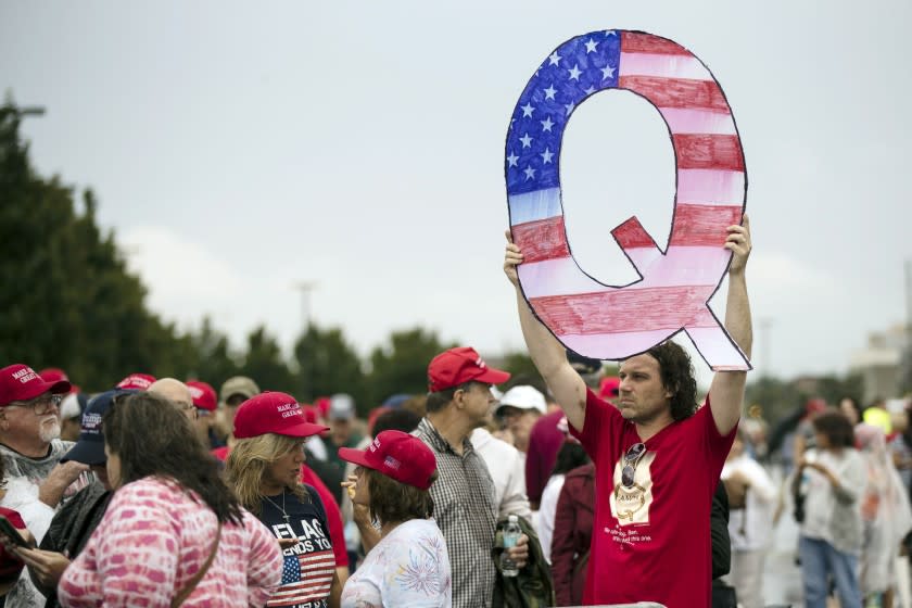 FILE - In this Aug. 2, 2018, file photo, David Reinert holding a Q sign waits in line with others to enter a campaign rally with President Donald Trump in Wilkes-Barre, Pa. A far-right conspiracy theory forged in a dark corner of the internet is creeping into the mainstream political arena. It's called QAnon, and it centers on the baseless belief that President Donald Trump is waging a secret campaign against enemies in the "deep state." (AP Photo/Matt Rourke, File)