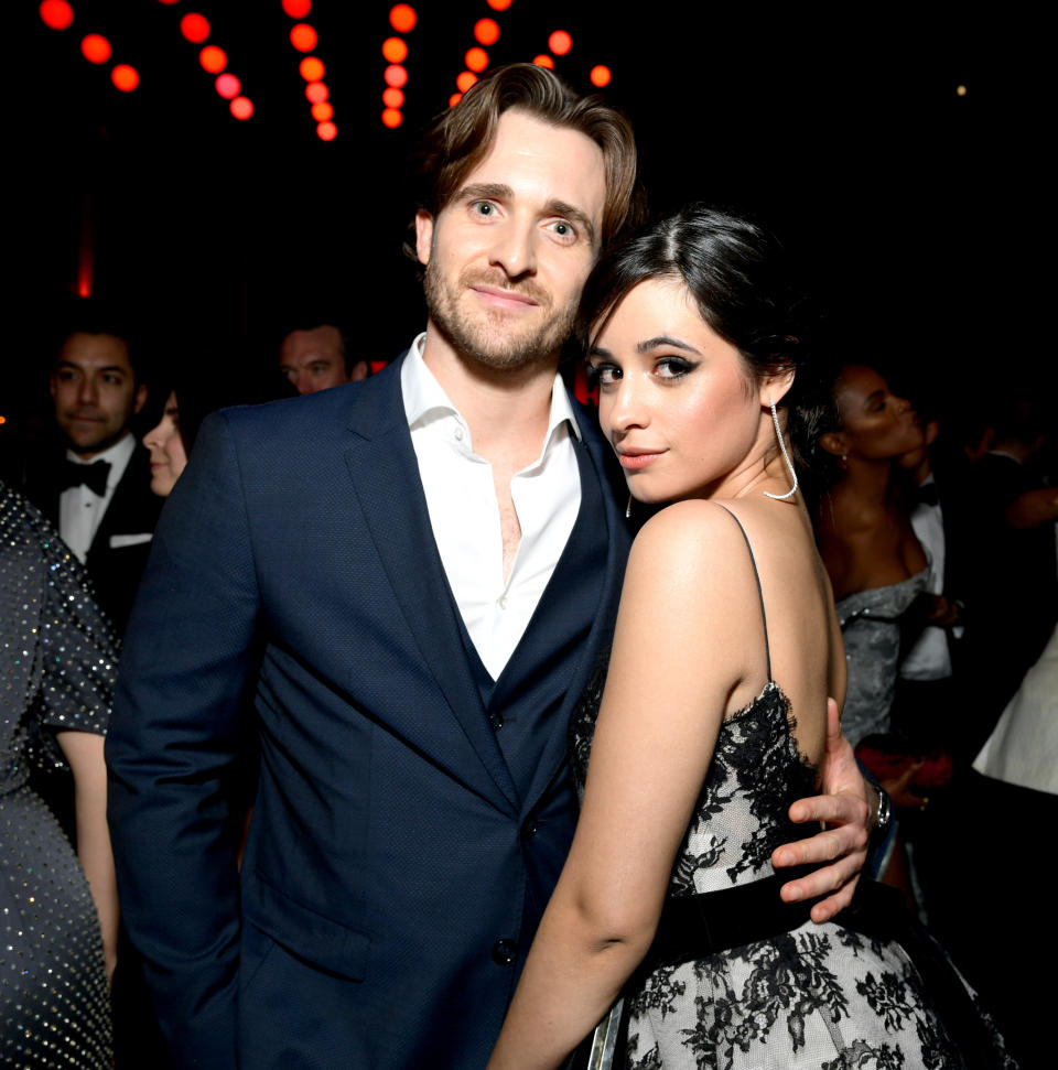 Man in a suit and woman in a black patterned dress at a social event