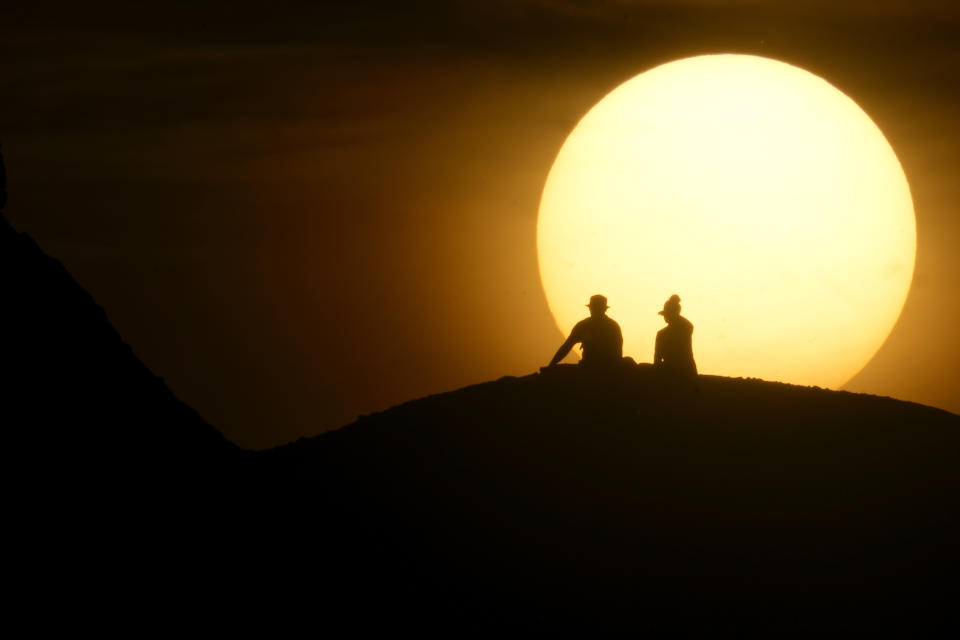 People watch the sun set at Papago Park, Saturday, March 9, 2024, in Phoenix. (AP Photo/Lindsey Wasson)