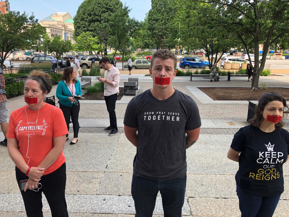 Anti-abortion protesters, who declined to give their names, stand outside the St. Louis courthouse where a judge is considering a case that would keep Missouri's only abortion clinic open Tuesday, June 4, 2019. (AP Photo/Jim Salter)