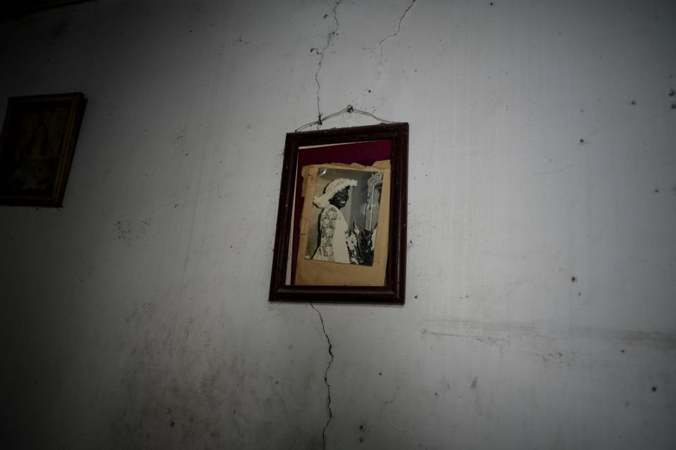An old photo of Regla Victoria Rodriguez hangs on a cracked wall inside a dilapidated mansion where six families live on Villegas Street in Havana, Cuba, Thursday, Oct. 5, 2023. The two-story building, which houses six families, is one of many, once luxurious houses that in recent years have partially collapsed or suffered visible damage. (AP Photo/Ramon Espinosa)