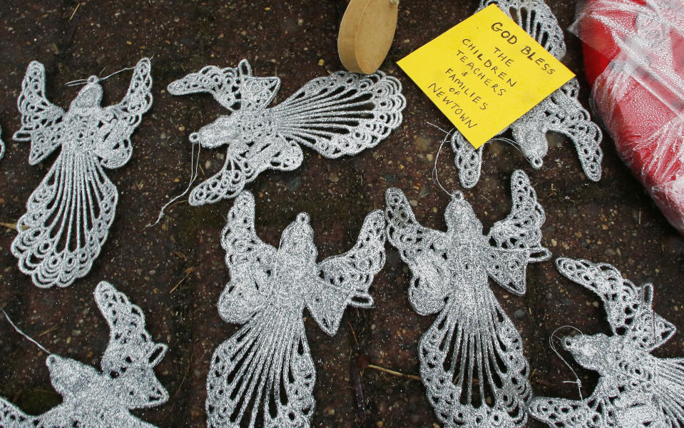 FILE - Angels and a note blessing victims rest on the ground at the site of a makeshift memorial for school shooting victims at the village of Sandy Hook in Newtown, Conn., Sunday, Dec. 16, 2012. A gunman opened fire at Sandy Hook Elementary School in the town, killing 26 people, including 20 children before killing himself. (AP Photo/Charles Krupa, File)