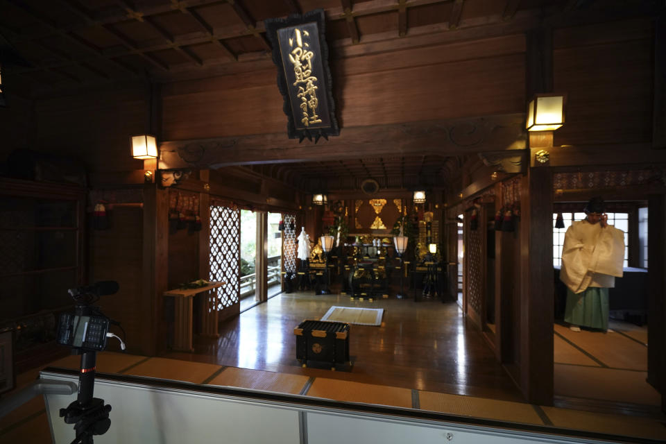 In this May 8, 2020, photo, Ryoki Ono, right, head priest, prepares to perform a livestream prayer during a 10-day trial of "online shrine" visit program at Onoterusaki Shrine in downtown Tokyo, allowing its visitors to join rituals from their homes. The shrine also accepted from worshipers their prayer messages, which were printed on a virtual wooden tablet each and offered to the Shinto gods to keep away evil spirits and the epidemic. (AP Photo/Eugene Hoshiko)